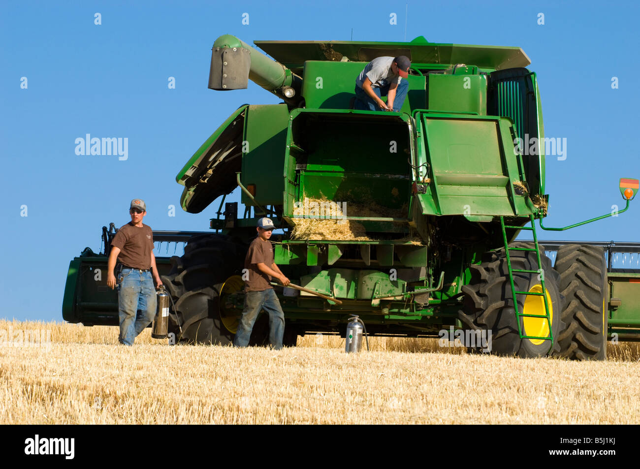 A harvest crew works quickly to contain a fire hazard from a malfunctioning combine in the Palouse area of Washington Stock Photo