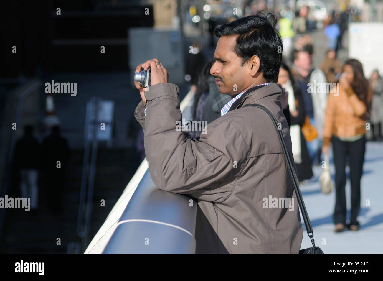 An Asian man taking a photograph from The Millenium Bridge, London, UK Stock Photo