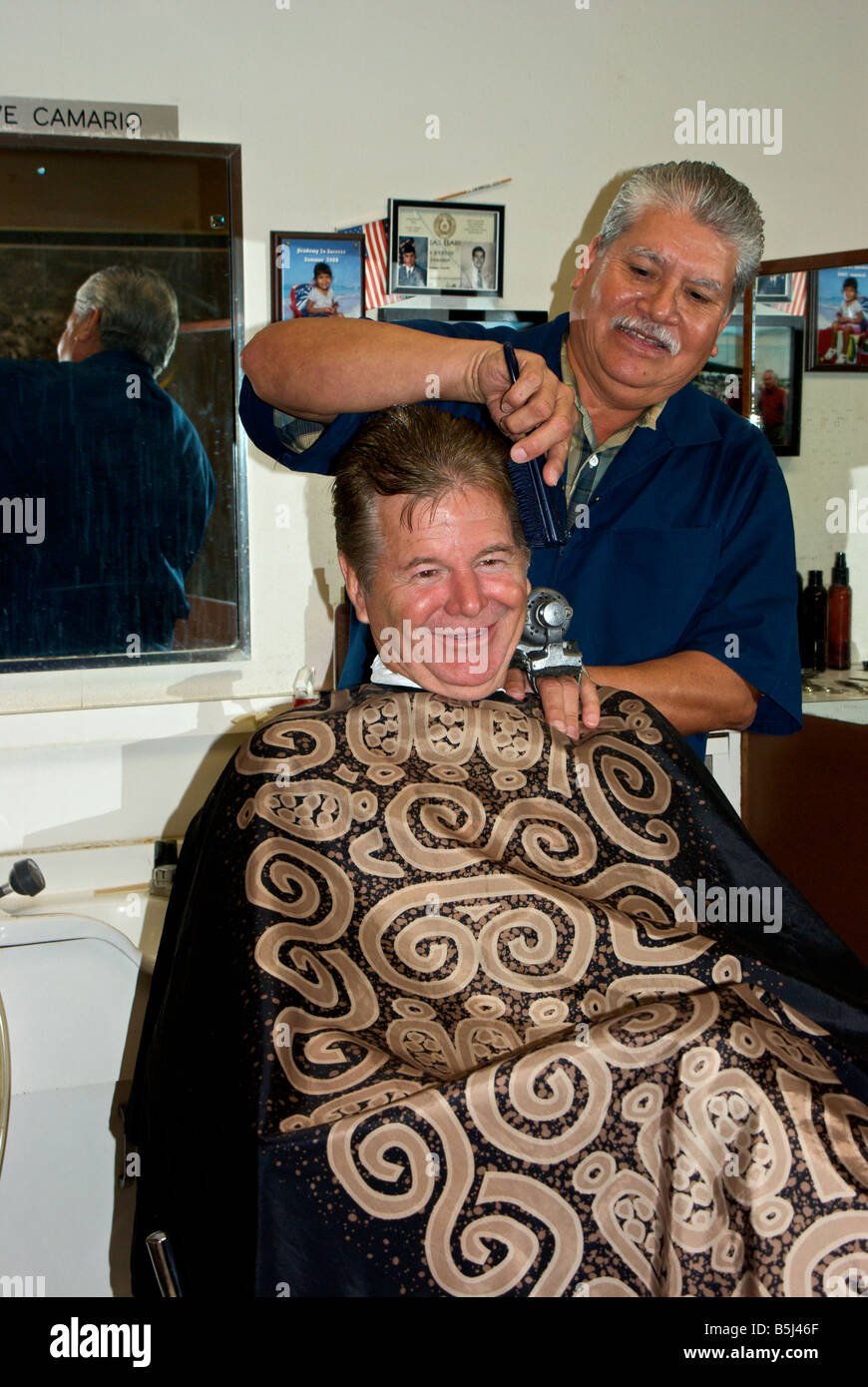 Male barber putting finishing touches on male customer in his shop in
