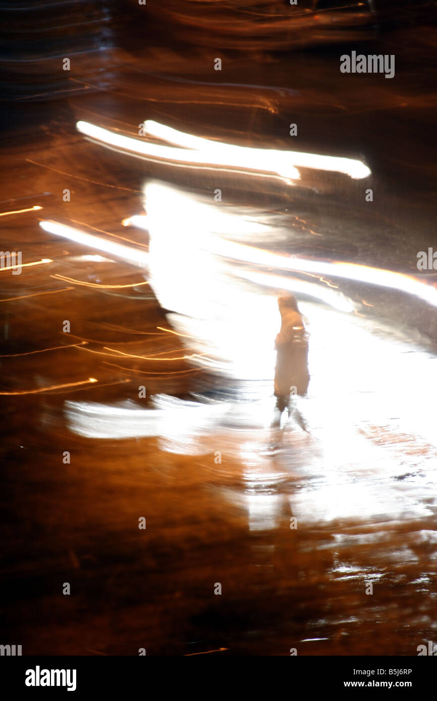 person crossing road heavy rain at night in town Stock Photo