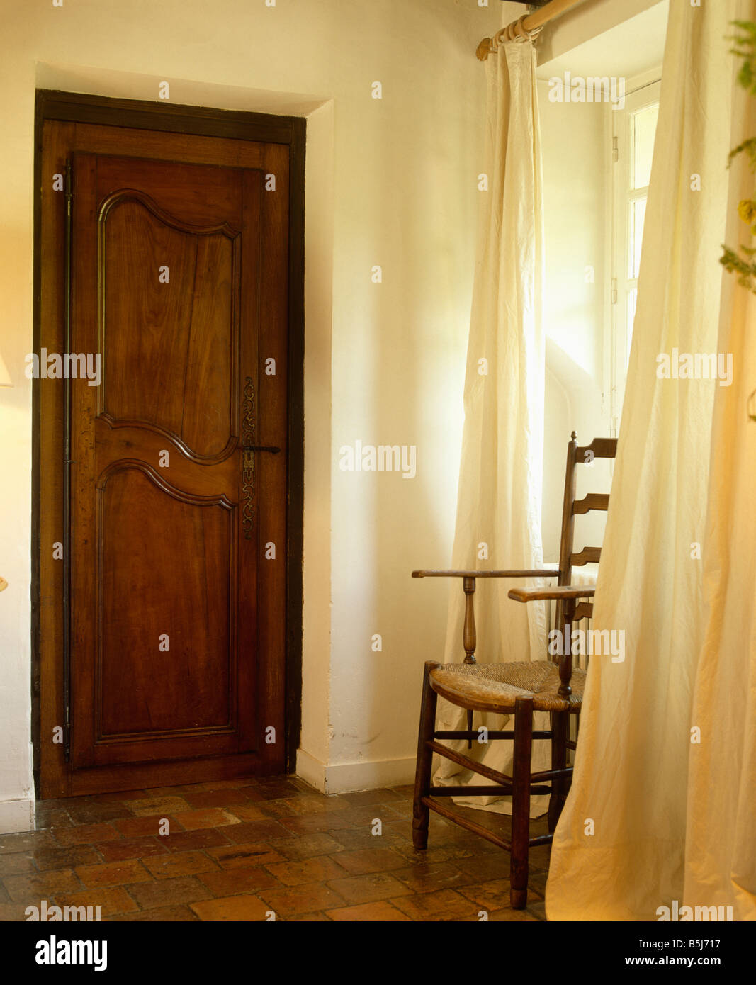 Hand-painted decoration on double doors in traditional with rush-seated  ladder-back chair and terracotta tiled floor Stock Photo - Alamy