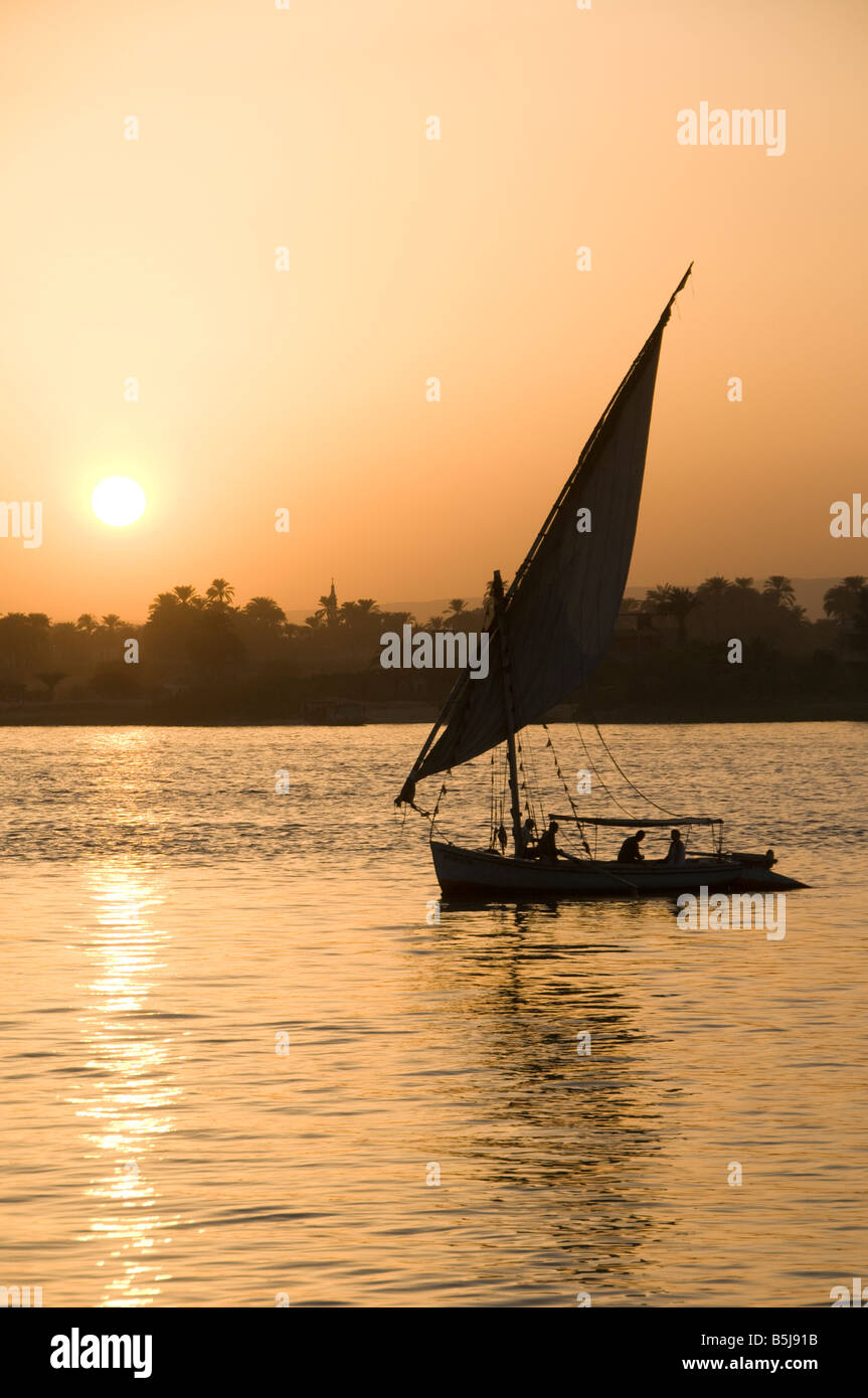 A silhouetted felucca traditional wooden sailing boat on the Nile river ...