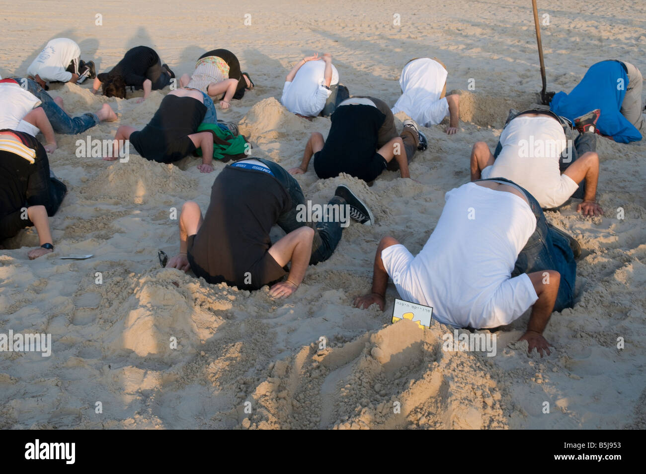 Young people burying their head in the sand during humorous event in