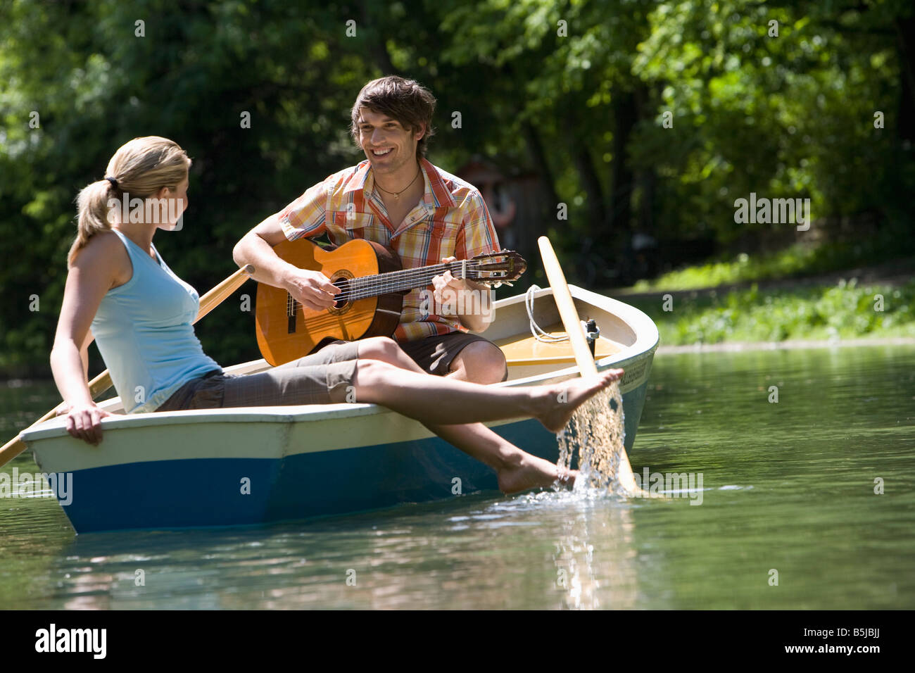 Young couple relaxing in rowing boat man playing guitar stock photo  alamy