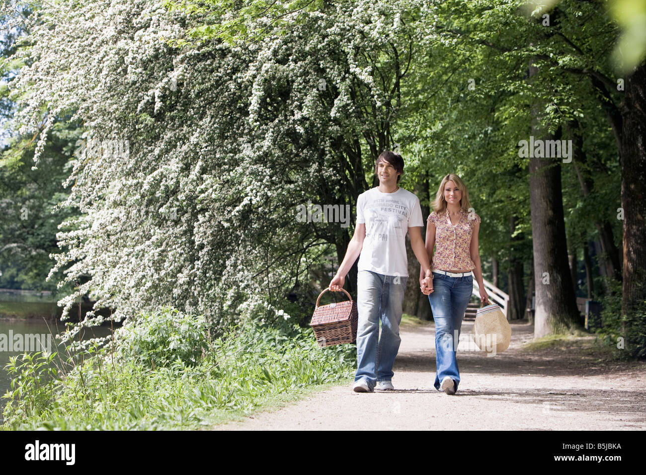 young couple walking hand in hand through park Stock Photo - Alamy