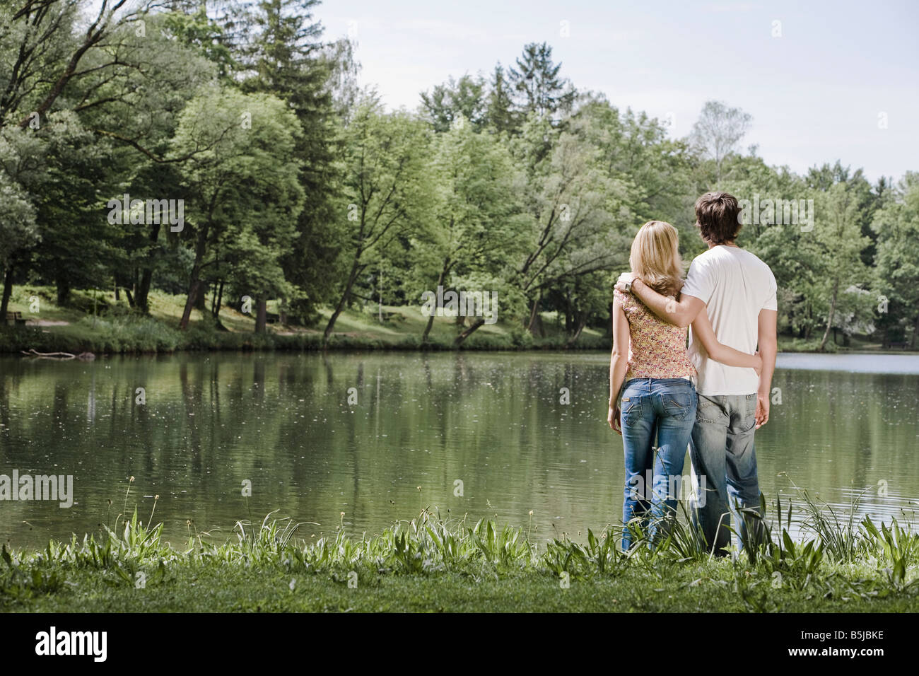 rear view of young couple standing by lake Stock Photo - Alamy