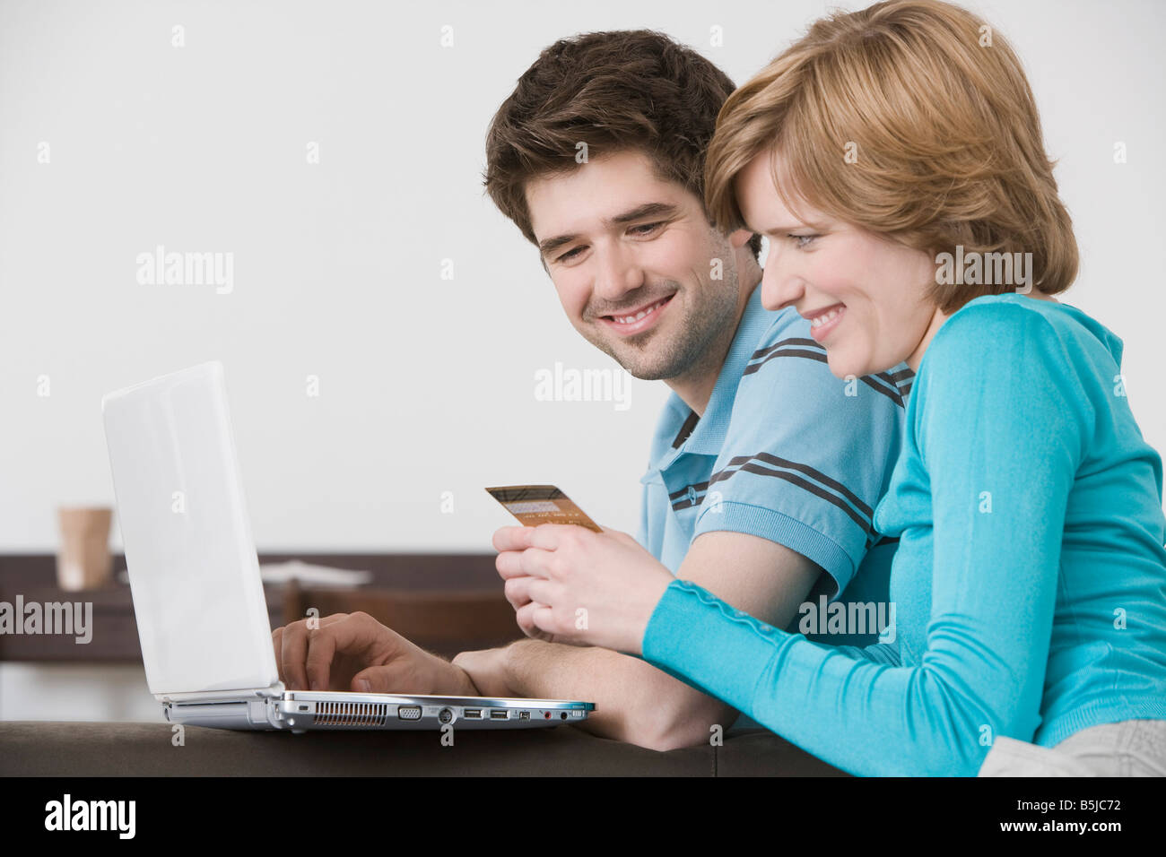 young couple in front of laptop computer with credit card Stock Photo