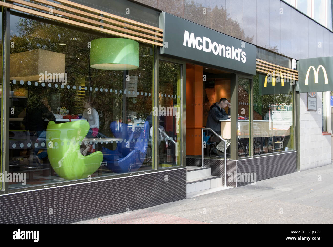 People sitting in and walking by McDonald s in Upper Street islington Stock Photo