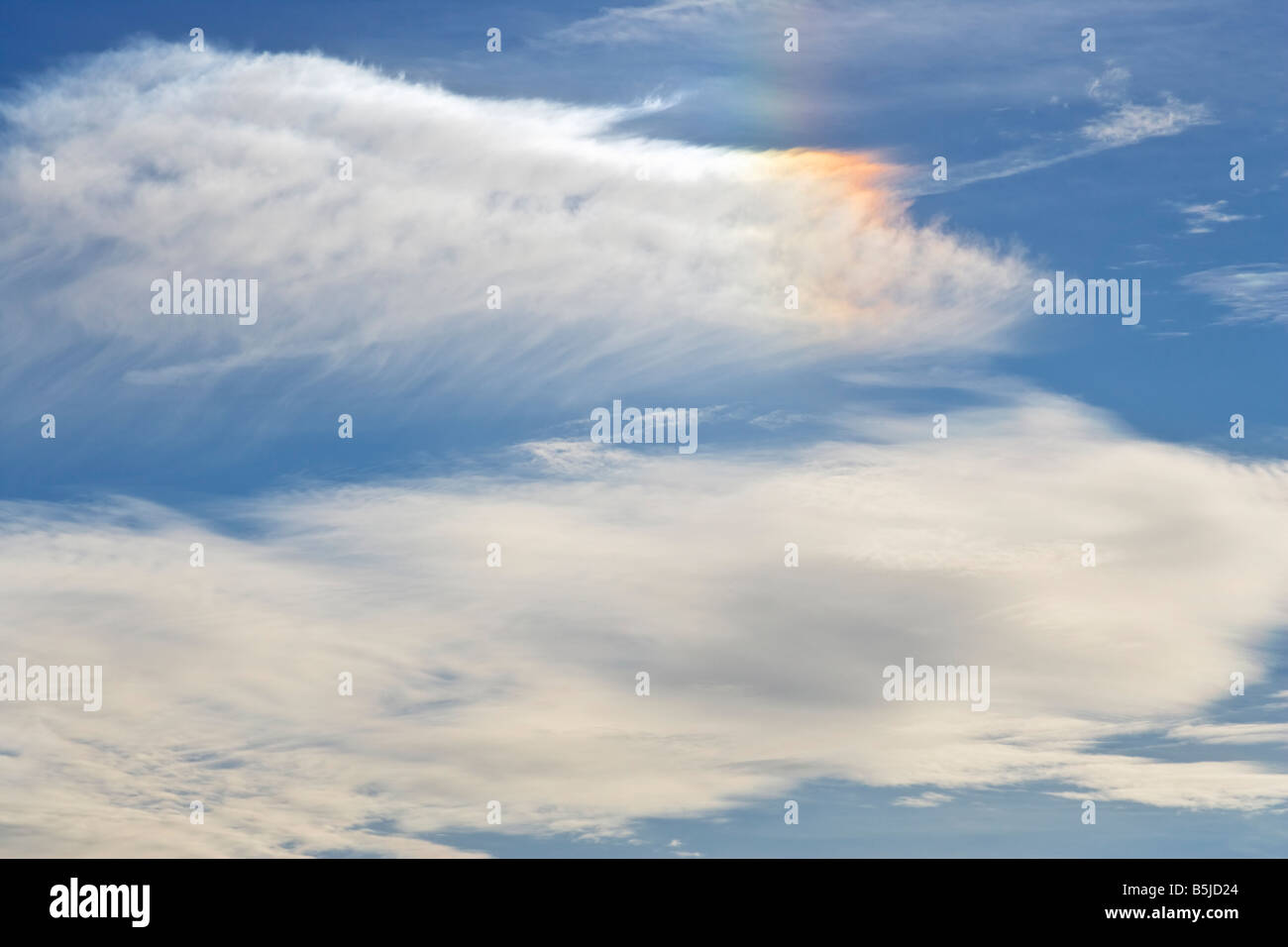 High altitude clouds and a rainbow coloured sun dog or parhelion caused by ice crystals refracting sunlight Stock Photo