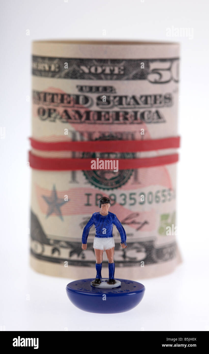 wad of 50 usa dollar bank notes cash tied up in a roll with elastic band behind toy footballer Stock Photo