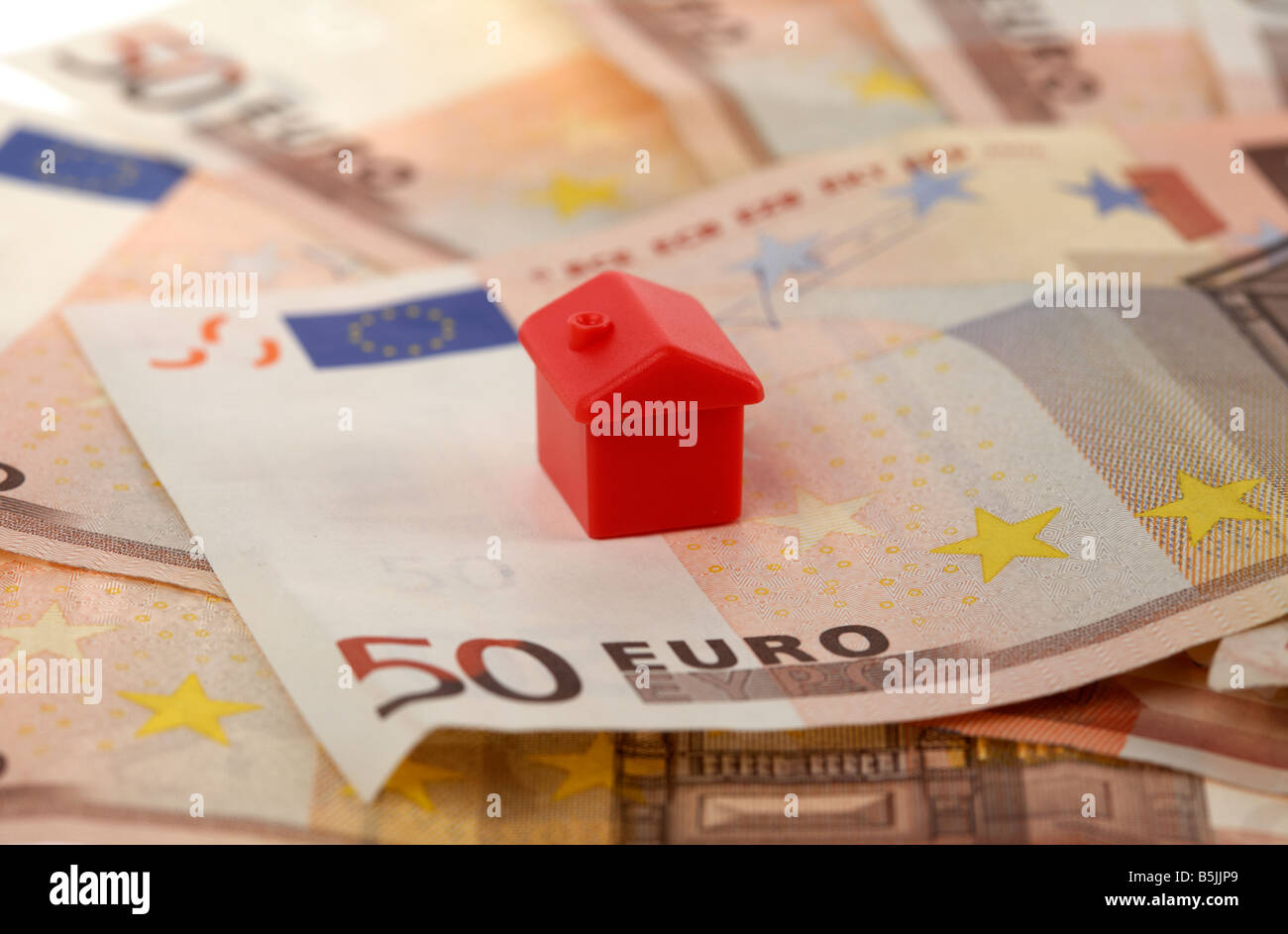one red house on top of a pile of 50 euro bank notes cash Stock Photo