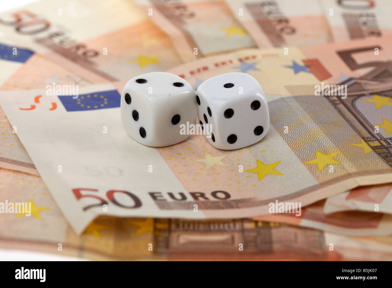 two dice on top of a pile of 50 euro bank notes cash Stock Photo