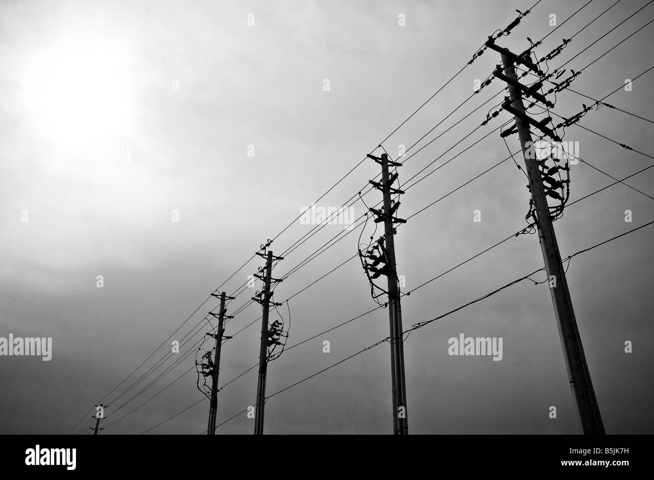 A row of electricity poles under a cloudy sky Stock Photo - Alamy