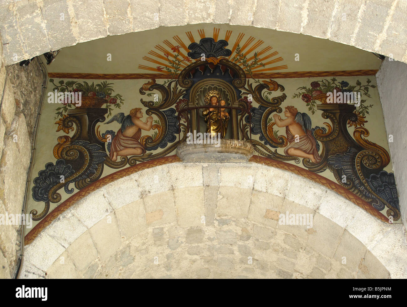 Stylised religious iconic art fresco painted under archway bridging thestreet near Pujada a la Catedral, Girona, Catalonia,Spain Stock Photo