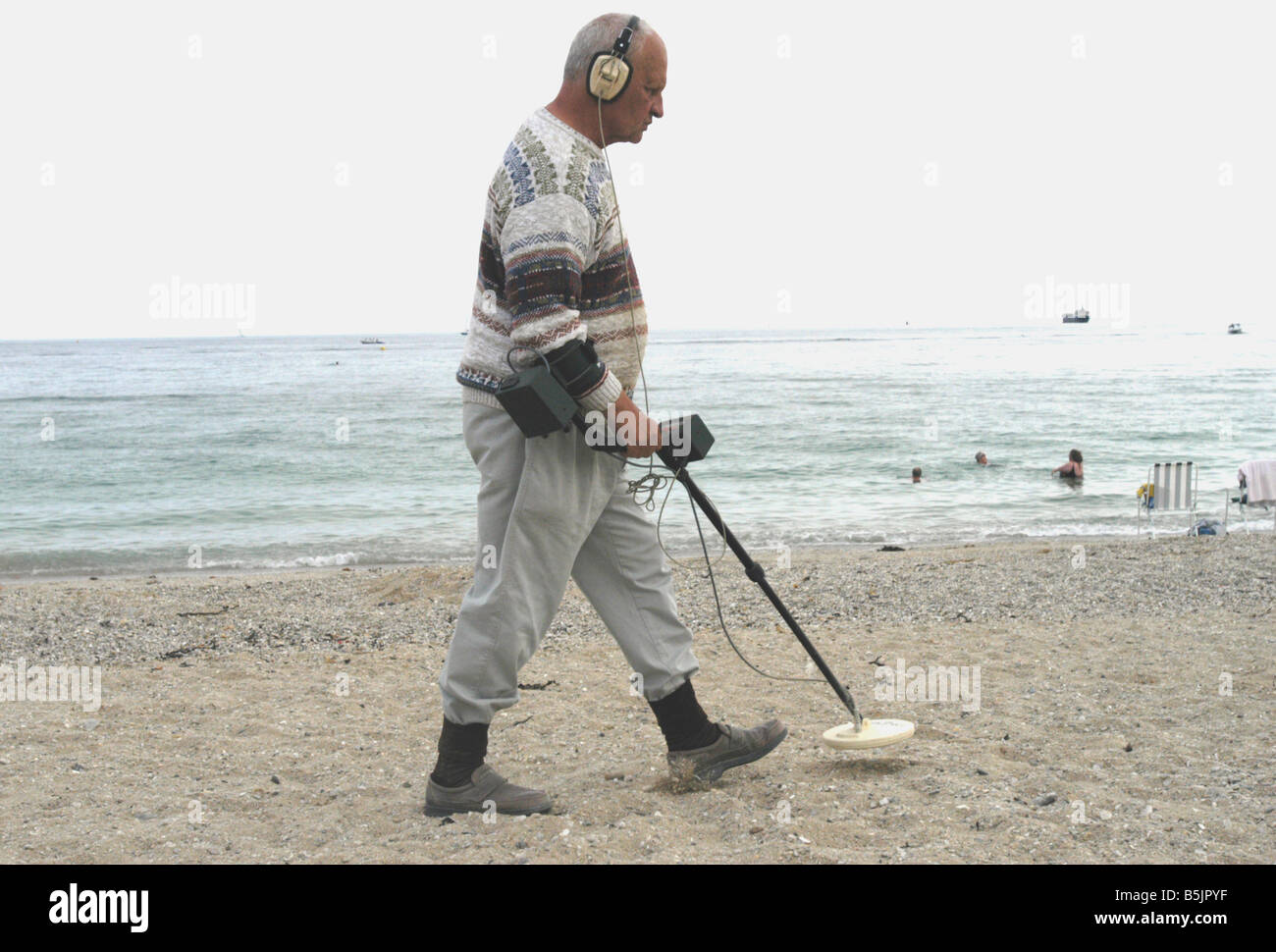 a man with a metal detector on a Cornish beach Stock Photo