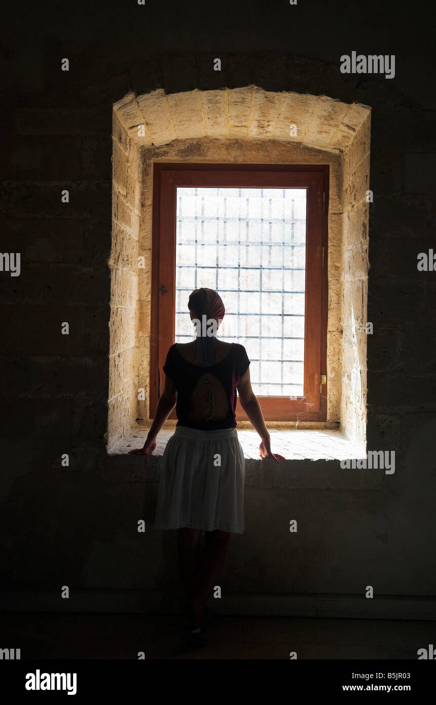 Silhouette of young woman looking out of window Stock Photo