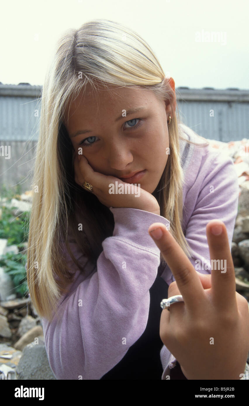 blonde teenage girl sticking two fingers up to onlooker Stock Photo