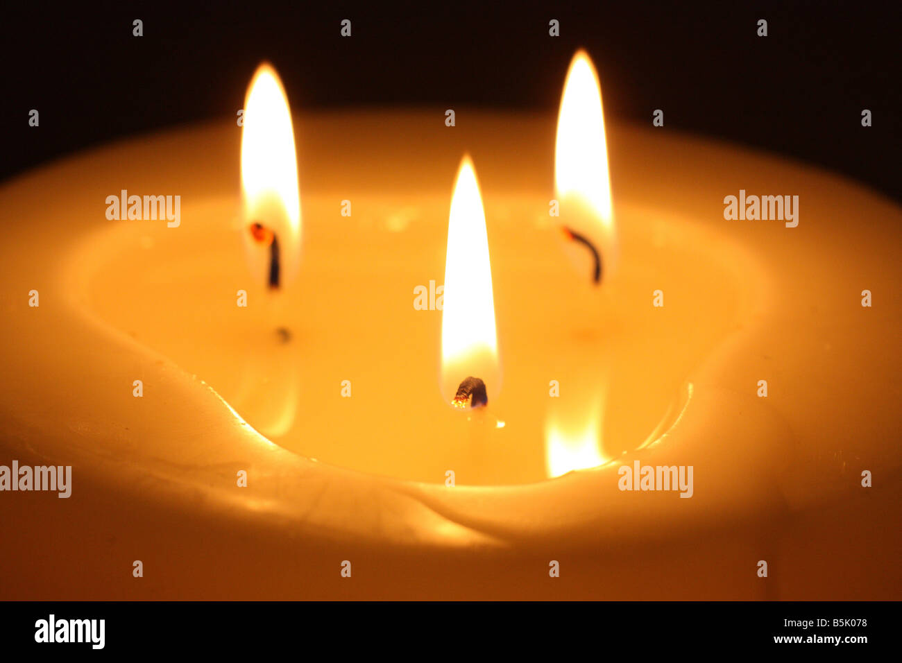 Burning candle with three wicks Stock Photo Alamy