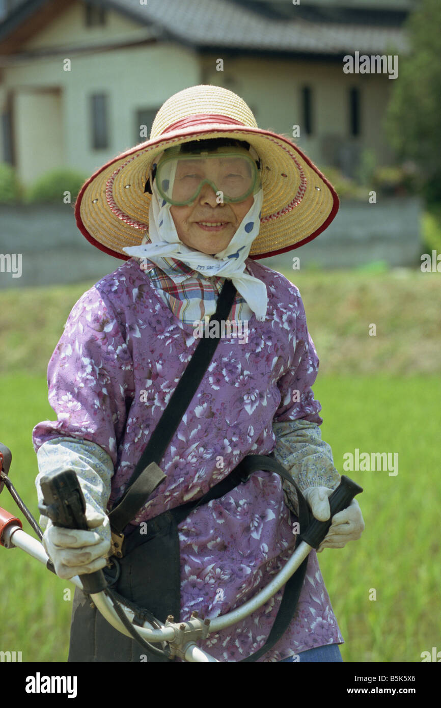 An elderly Japanese woman cutting grass Stock Photo Alamy