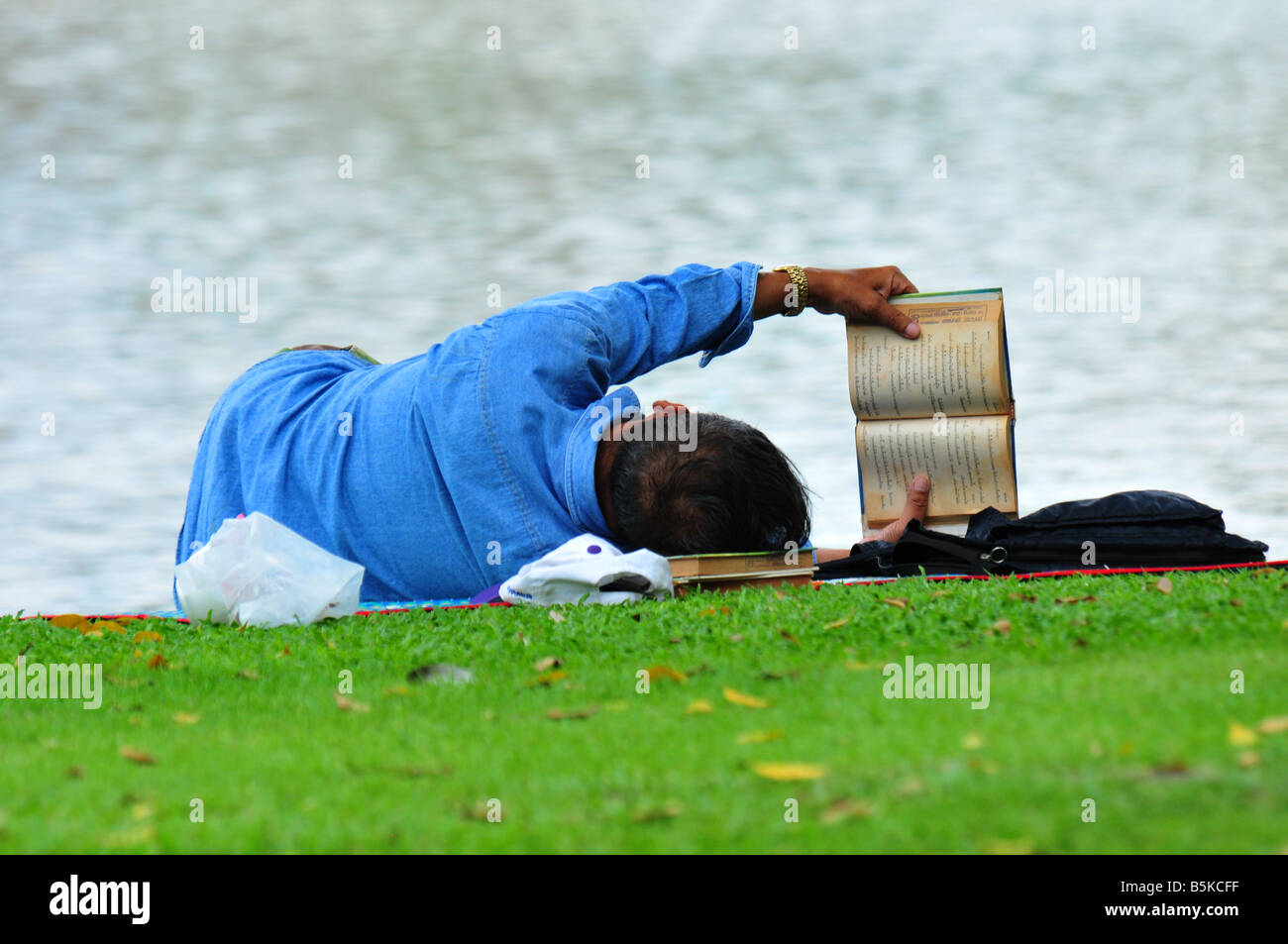 Bangkokian man reading book beside the pool at Chatuchak park, Bangkok,Thailand. Stock Photo