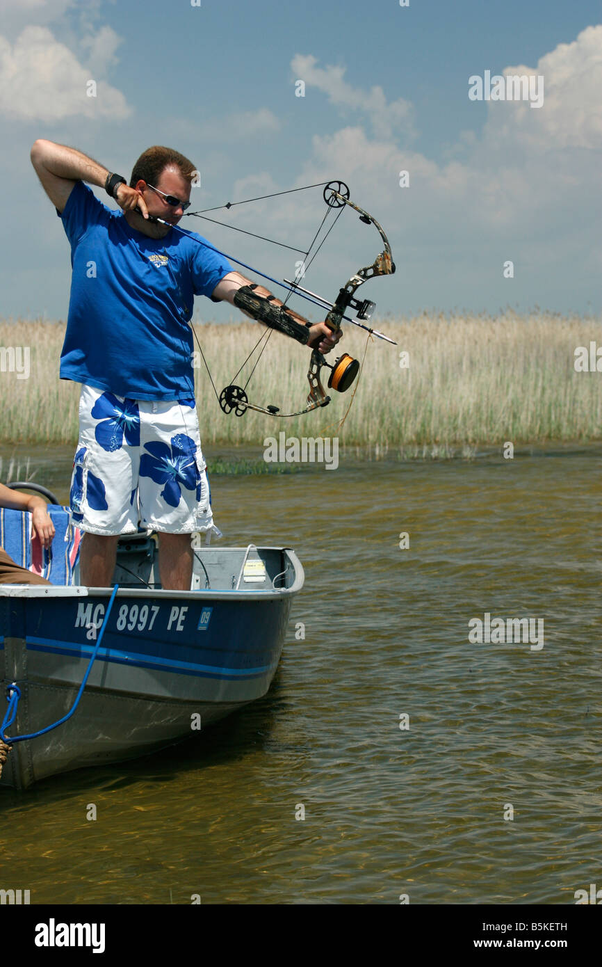 Man drawing his compound bow and aiming at a fish Stock Photo - Alamy
