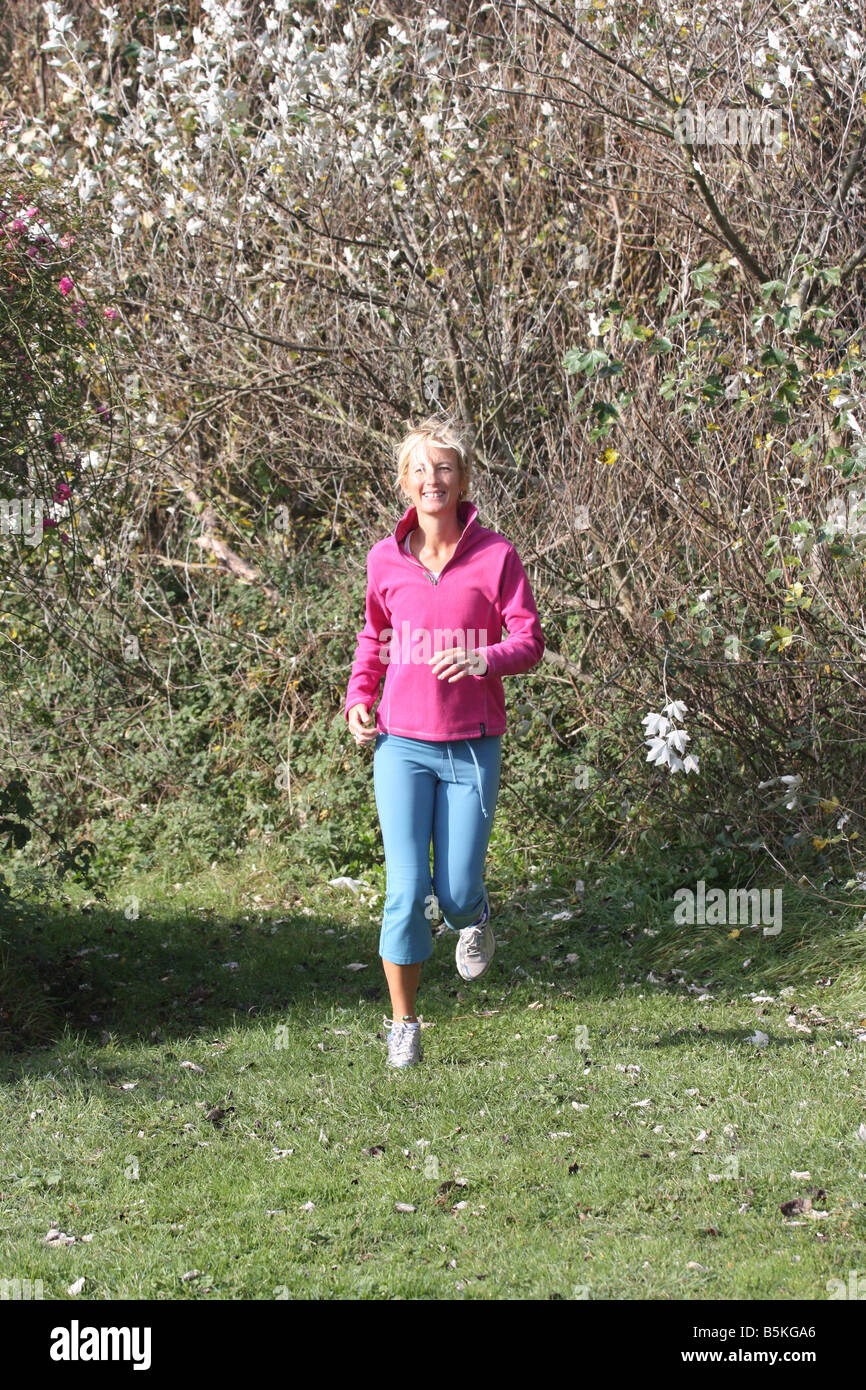 Young blonde woman outdoors. Jogging in countryside. Stock Photo
