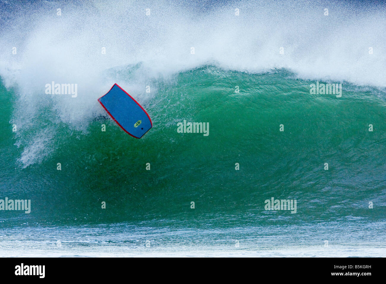 Wipeout, surfboard emerging from wave, Cornwall, UK, with space around subject for copy or graphic. Stock Photo