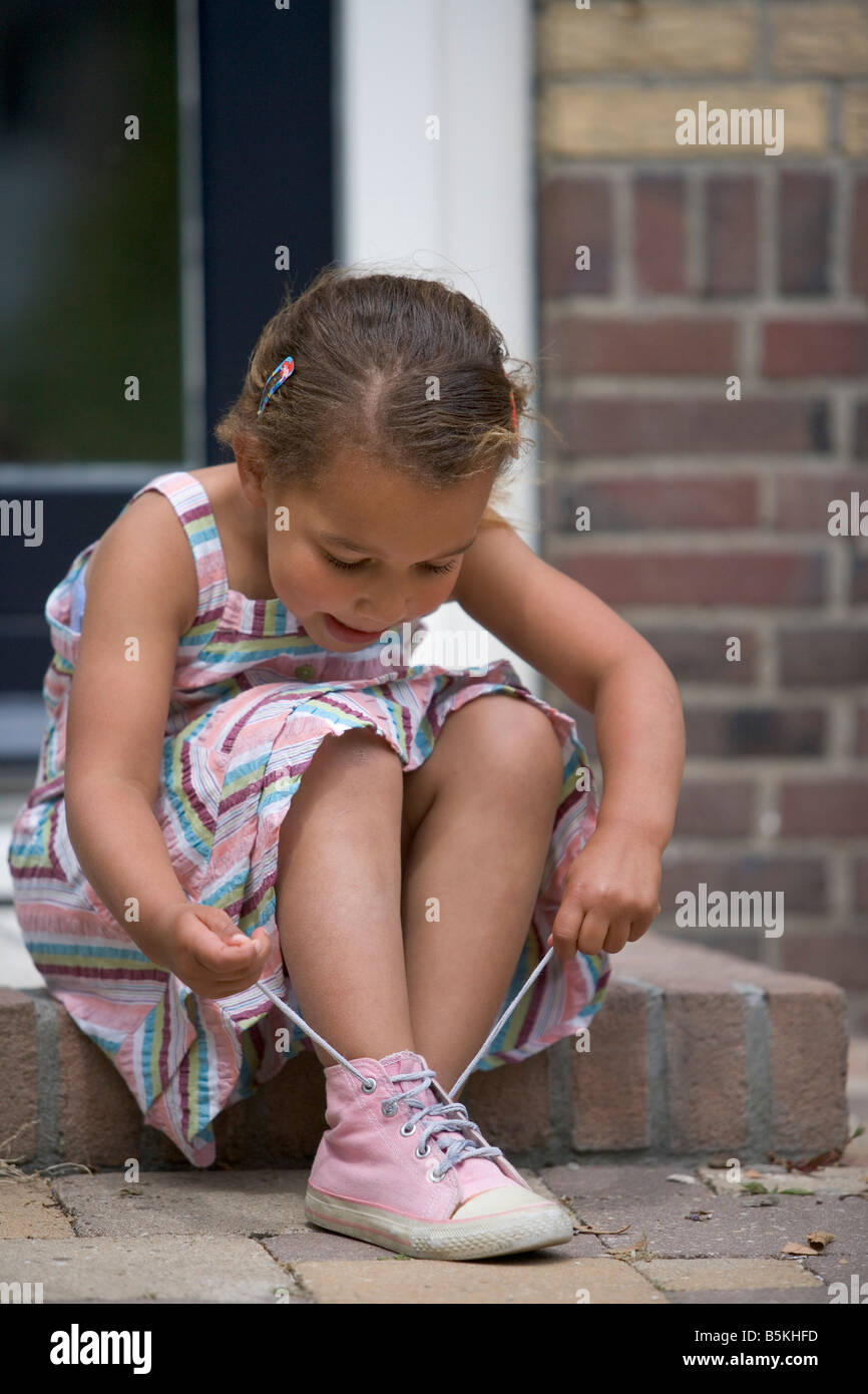 Little girl is fixing her shoe laces Stock Photo