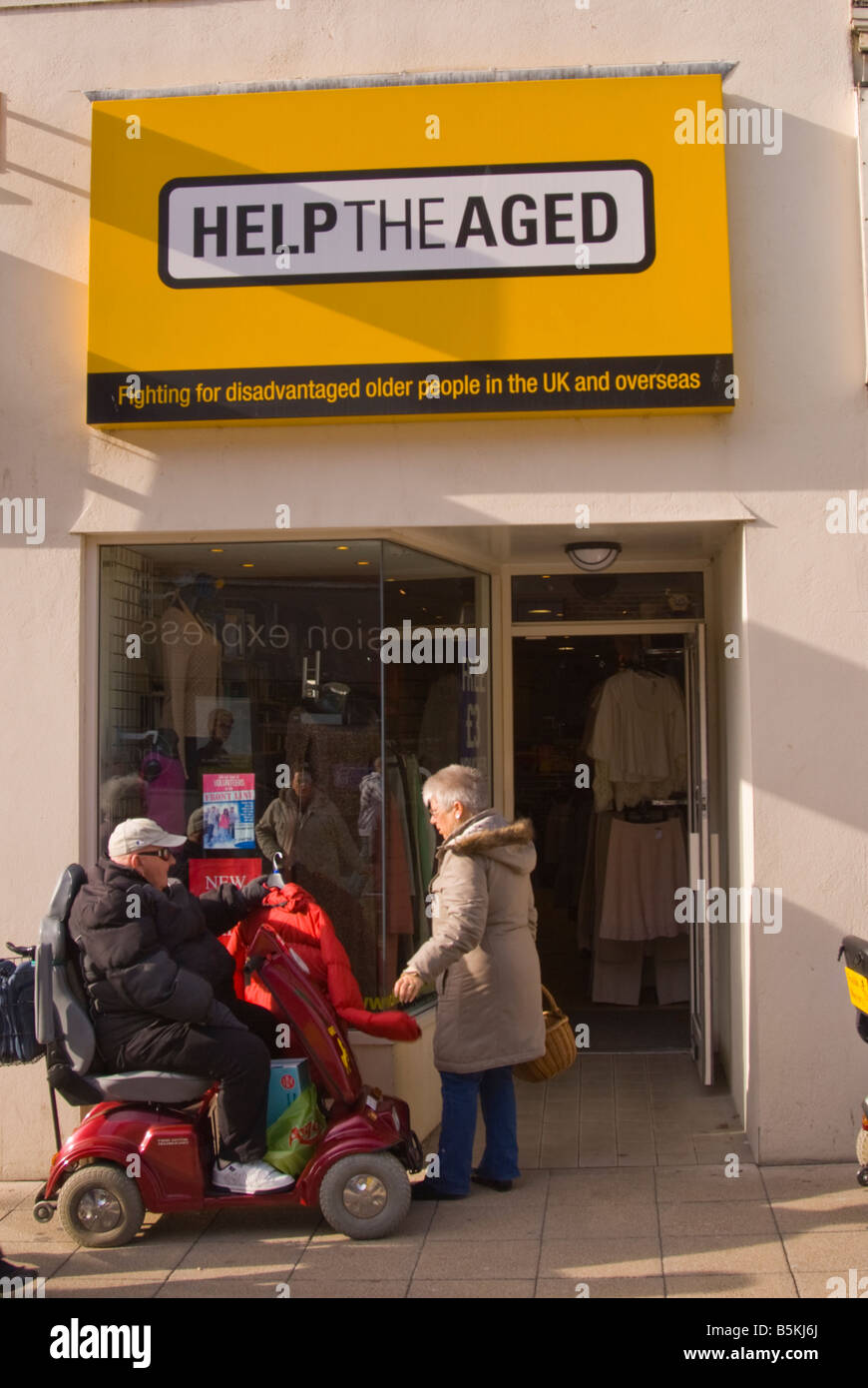 Man on a mobility scooter outside "Help The Aged" shop in Lowestoft
