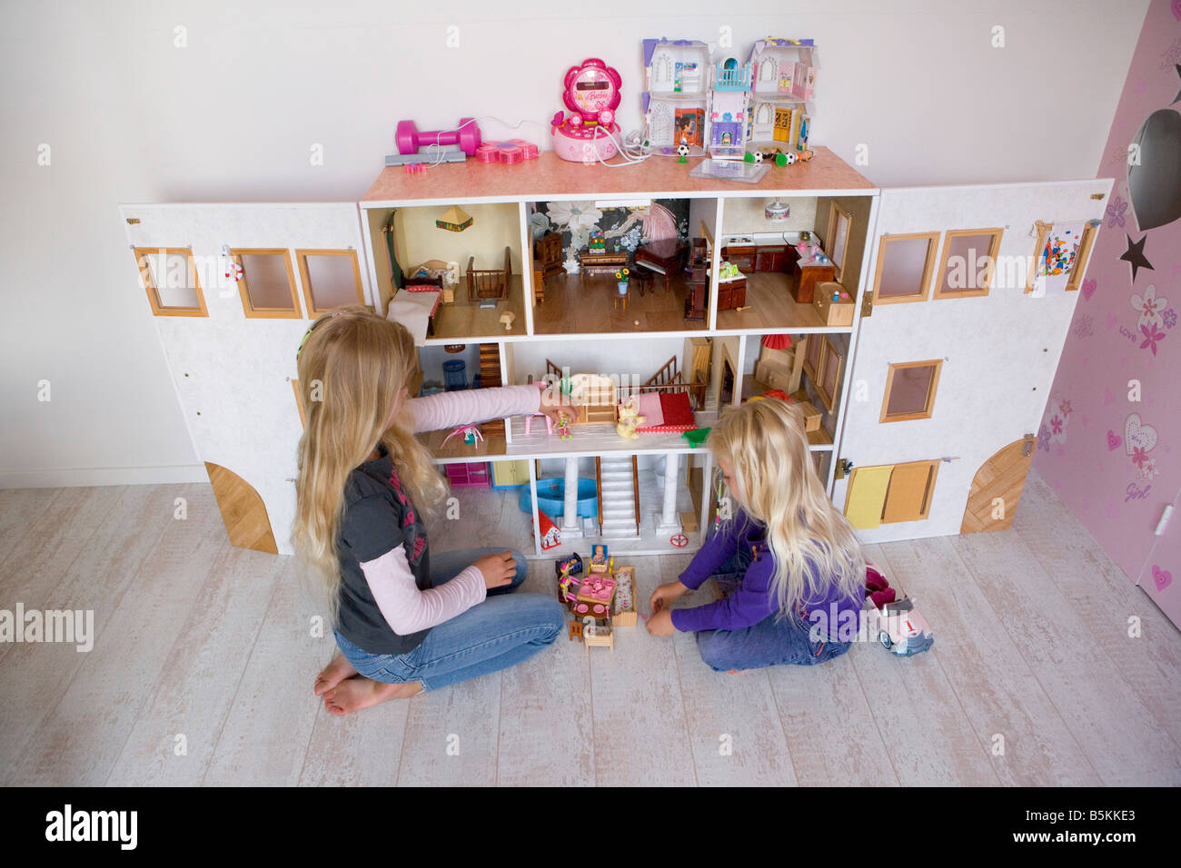 Two girls playing with a doll s house Stock Photo