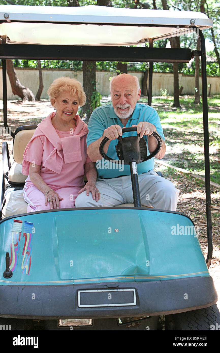 A senior couple in a golf cart The man wants to drive fast Stock Photo