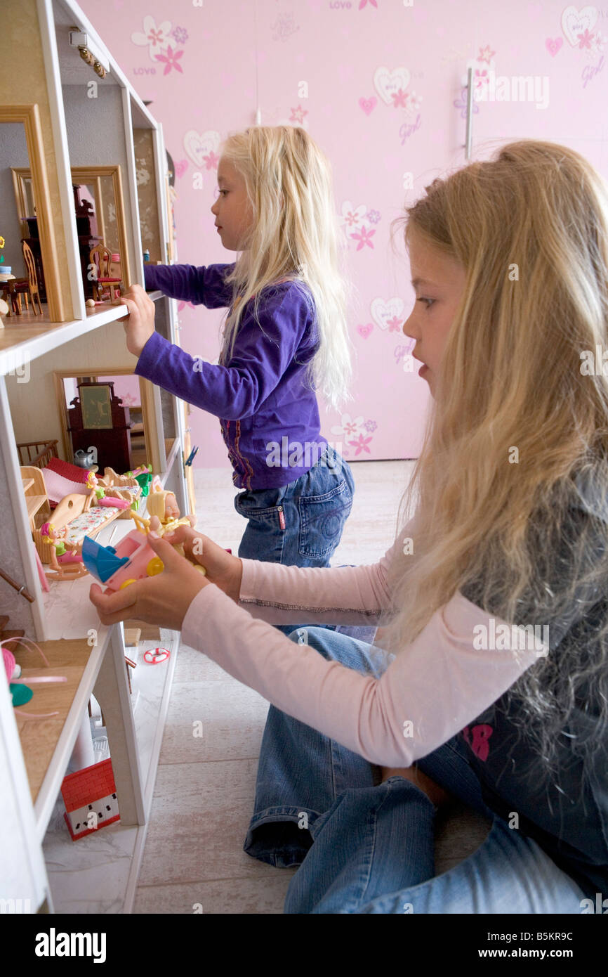 Two girls playing with a doll s house Stock Photo