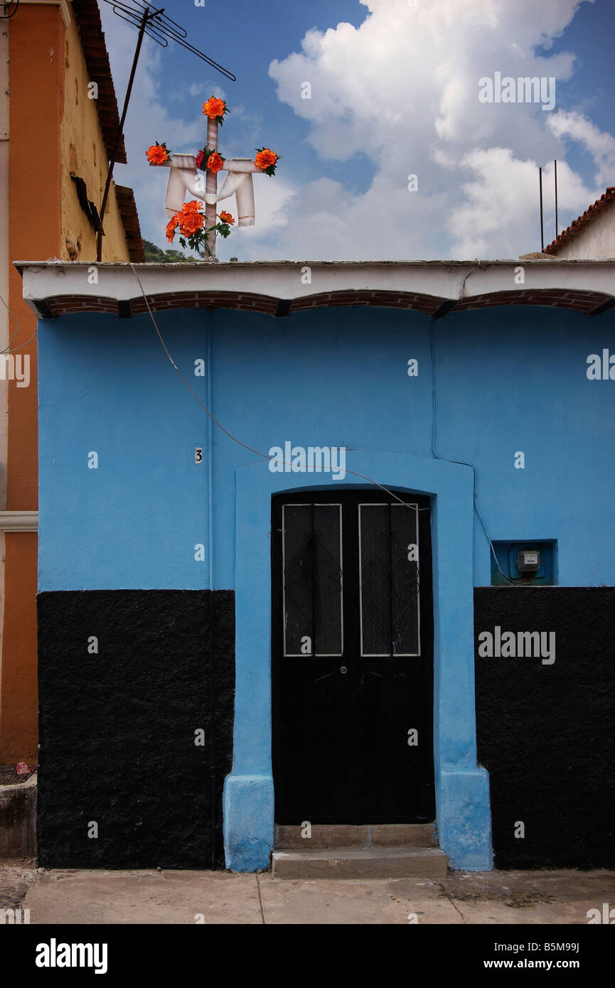 A blue house with black door and cross with orange flowers in Ajijic