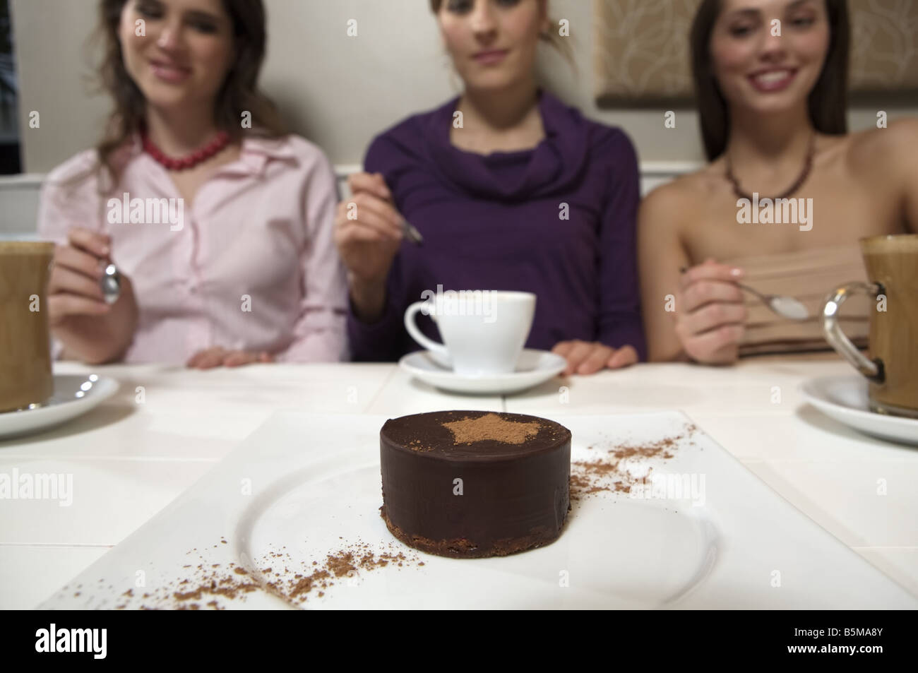 Three women contemplating  a chocolate tart. Stock Photo