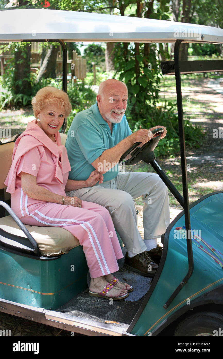 An active senior couple driving a golf cart Stock Photo