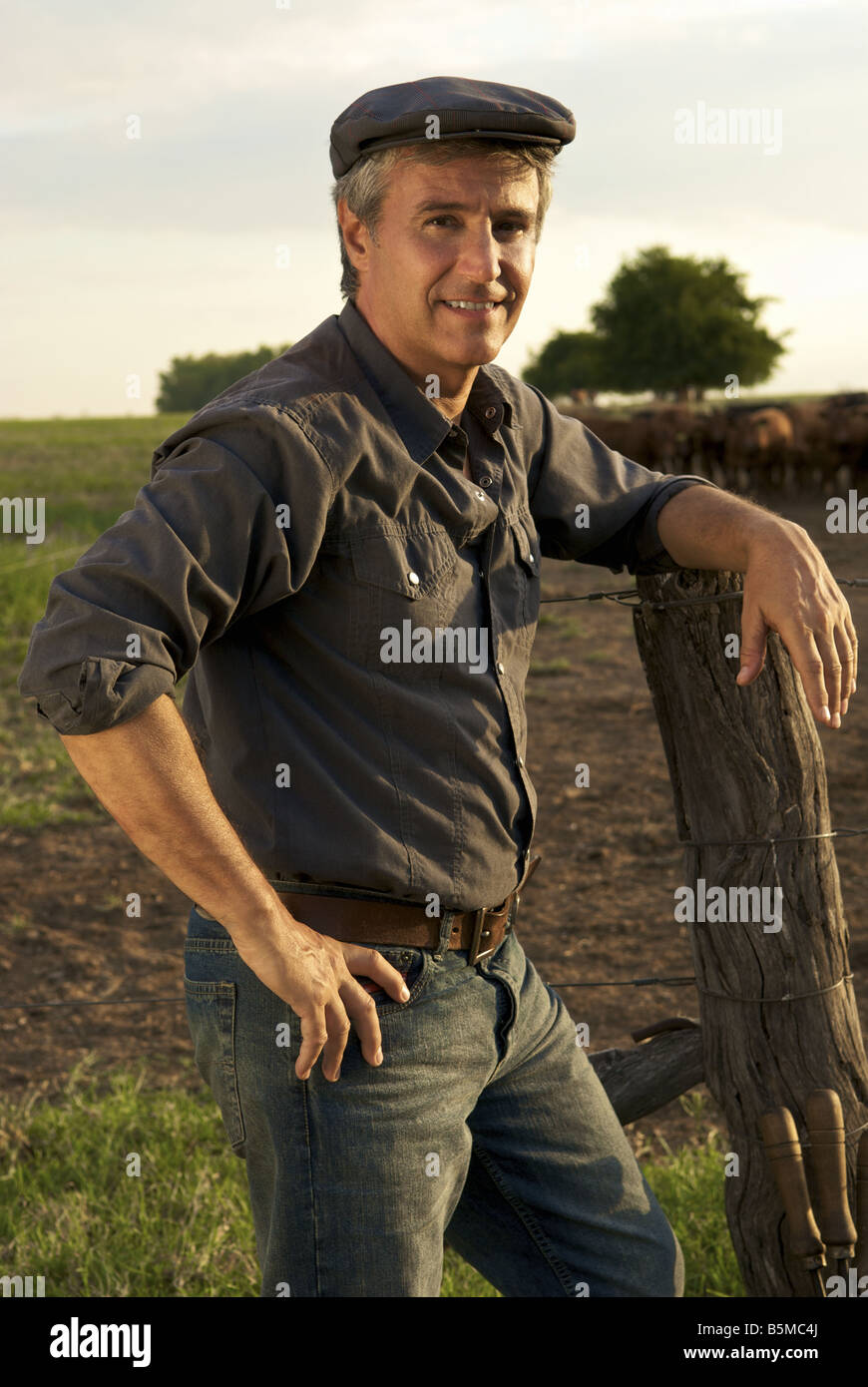A man on a ranch leaning on a fence post Stock Photo Alamy