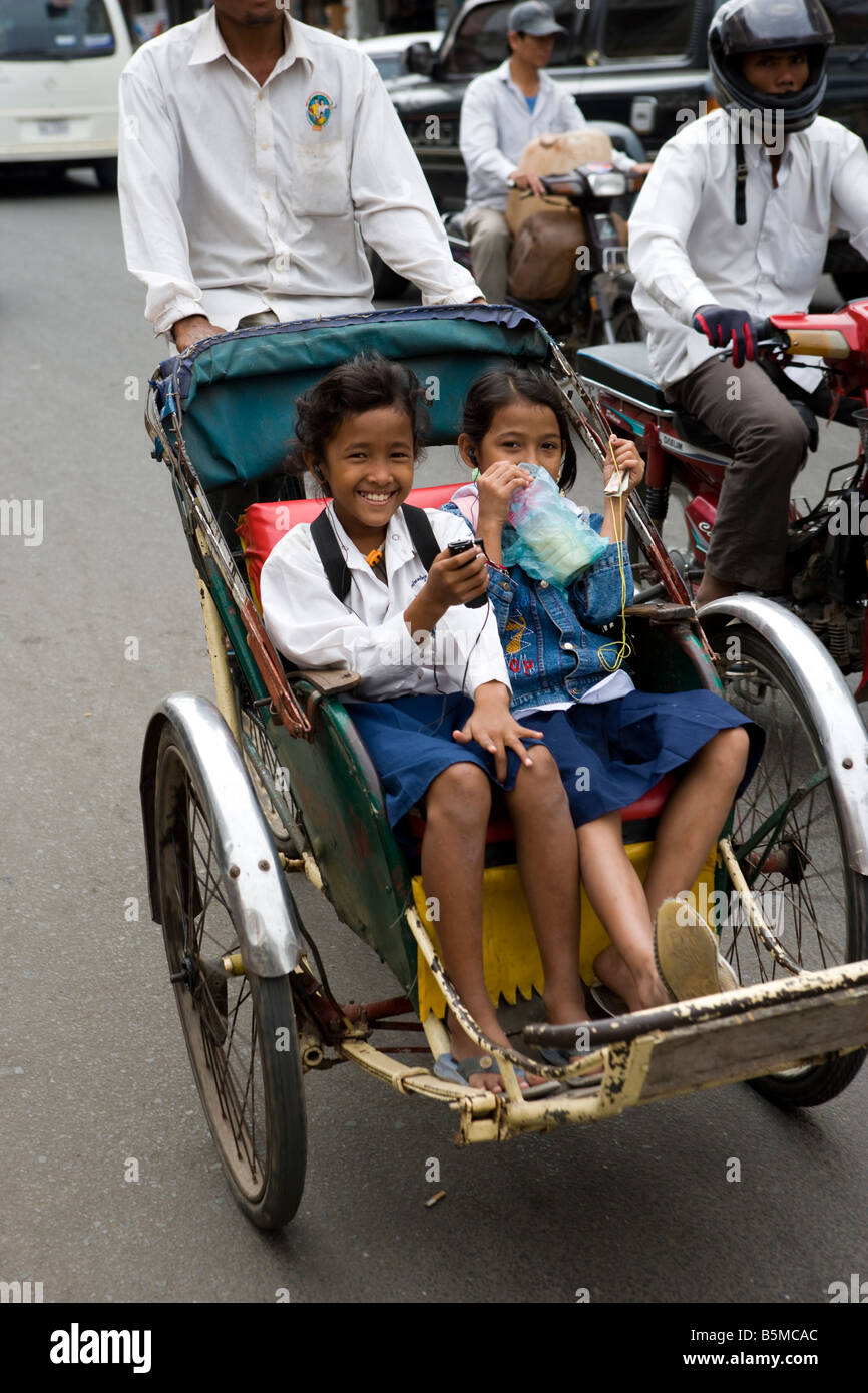 Cyclo driver carrying children in Phnom Penh Cambodia Stock Photo