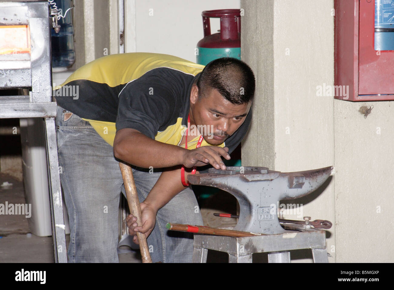 A blacksmith working on a horse shoe at an exhibition in Terengganu, Malaysia Stock Photo