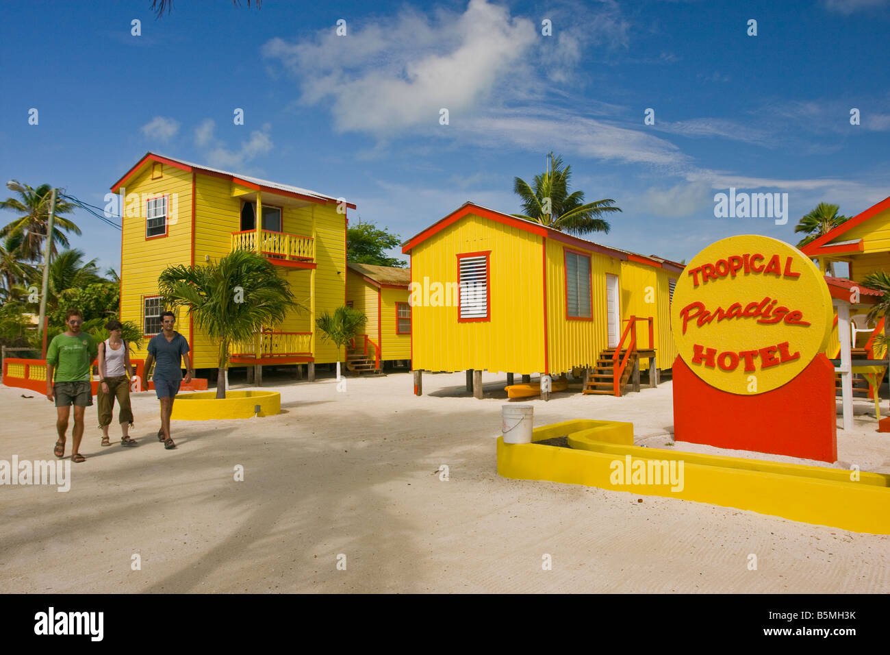 CAYE CAULKER BELIZE - Tourists walk by the Tropical Paradise Hotel on the beach. Stock Photo