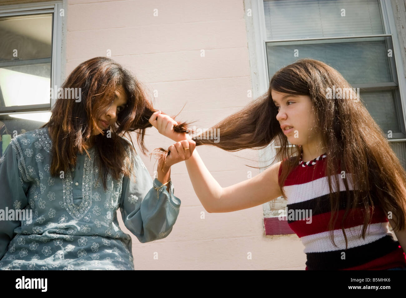Young Indian woman and her preteen Caucasian stepsister pulling each other s hair MODEL RELEASED Stock Photo