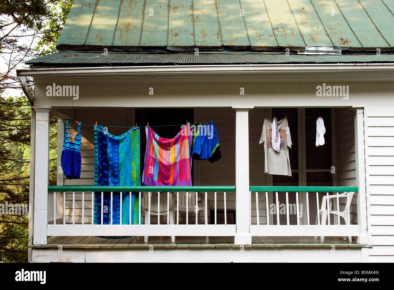Summer clothes dry on a strung clothesline across a porch Stock Photo