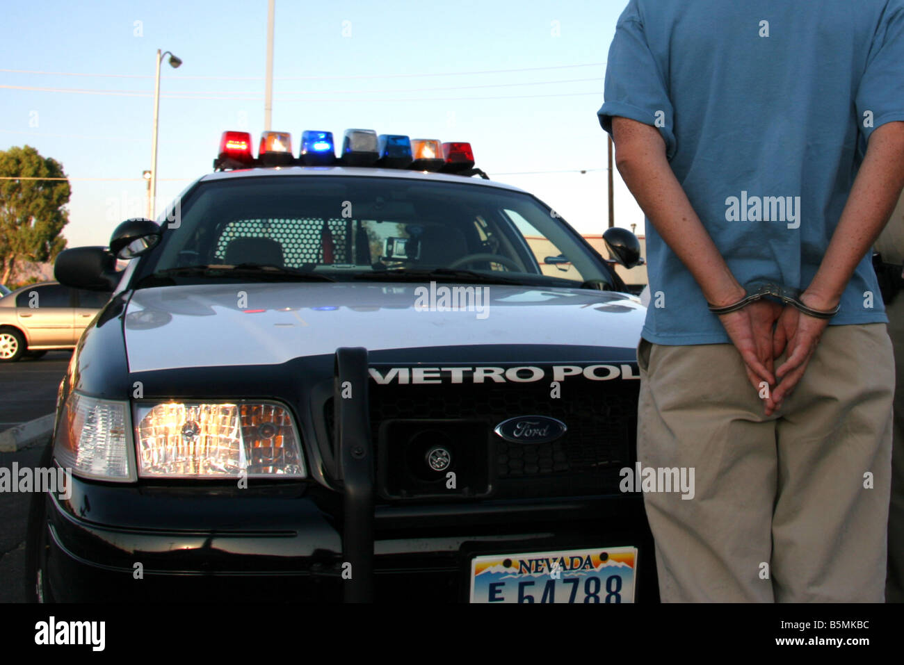 Man in handcuffs stands infront of a Las Vegas Police car Stock Photo