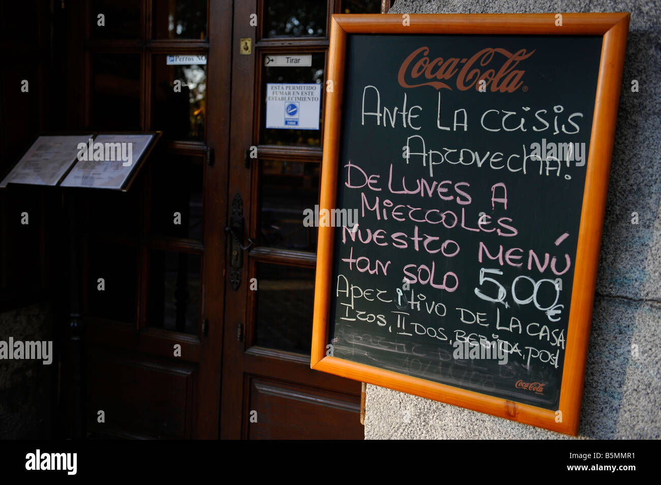 A restaurant sign reads 'Take advantage during the credit crisis with menu for only 5 euros from Monday to Wednesday.' Stock Photo