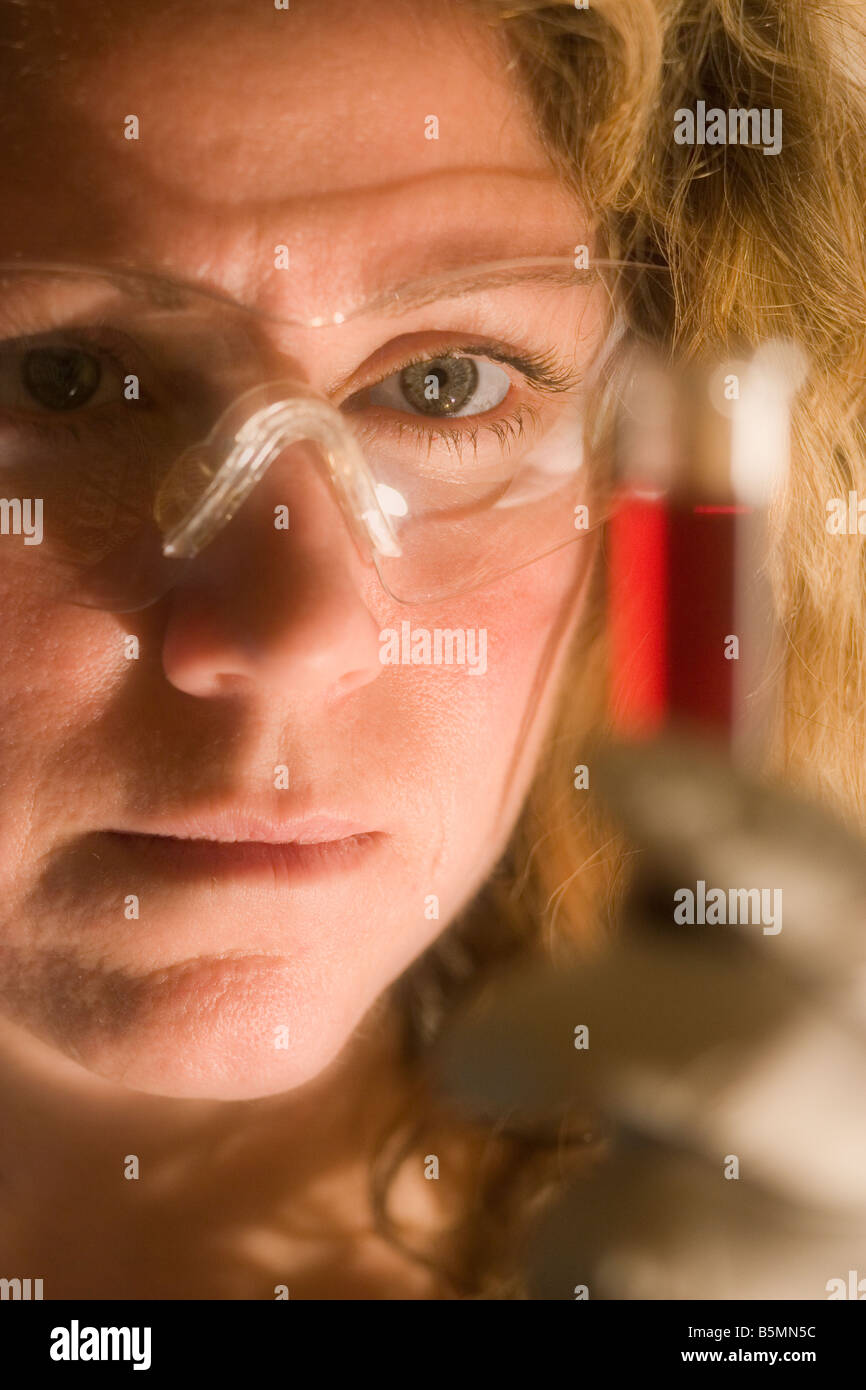 Female scientist examines a red solution in a test tube. Stock Photo