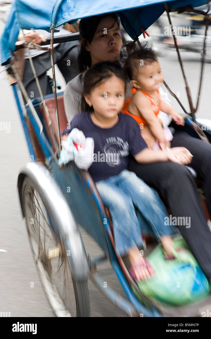 Cyclo driver carrying children in Phnom Penh Cambodia Stock Photo