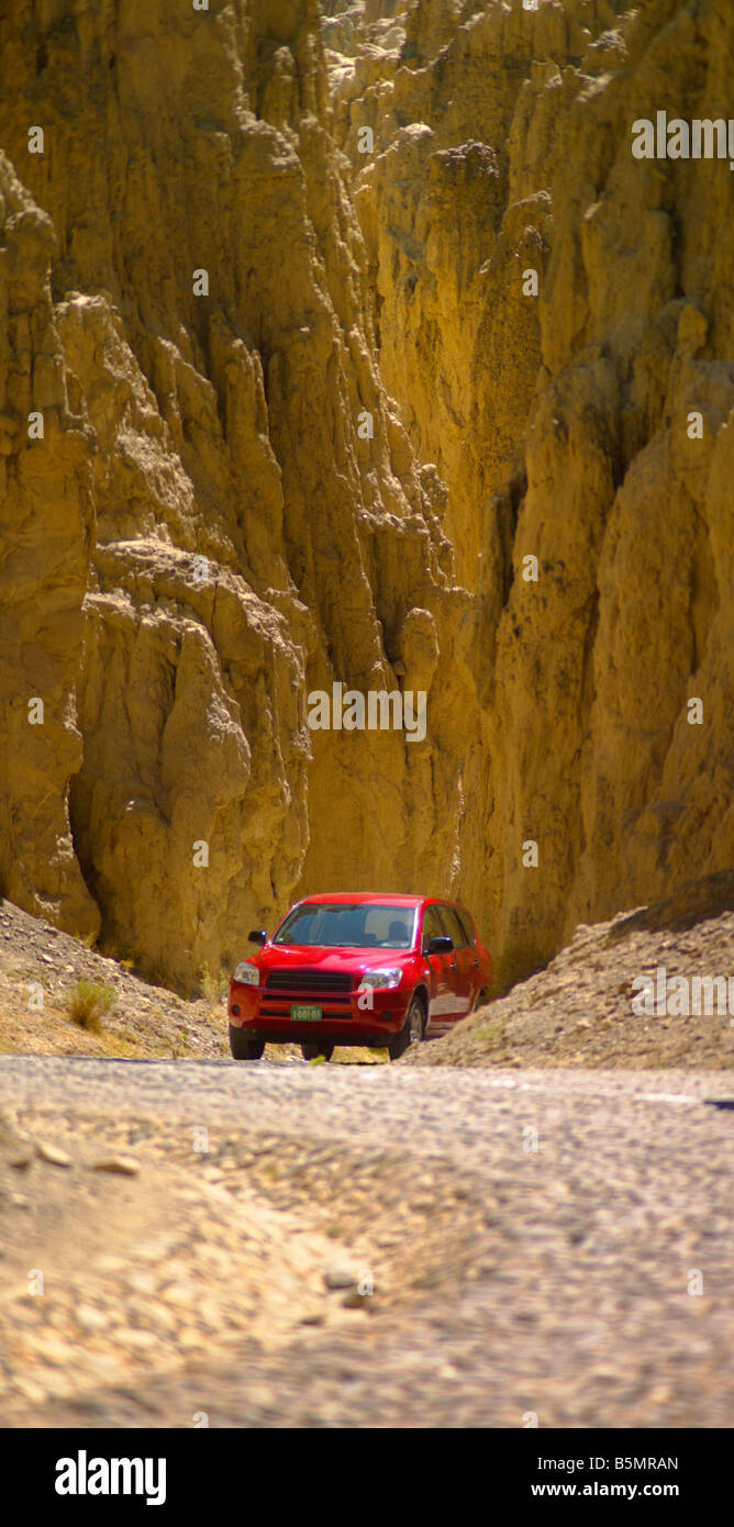Red car winding road yellow rocky mountain trip touristic peak curve landscape vertical 4x4 truck Stock Photo