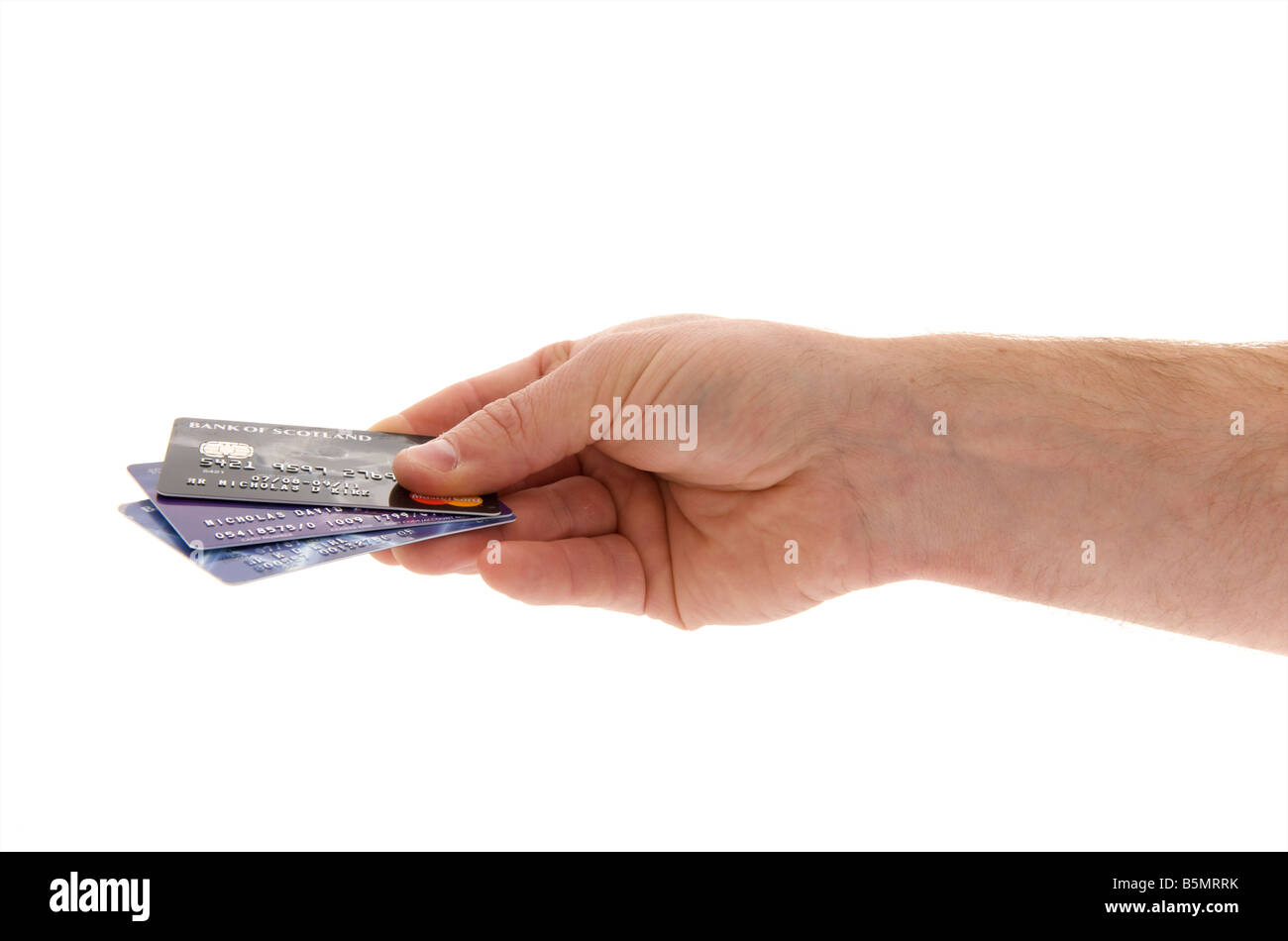 mans male right outstretched hand holding a selection of credit cards against a white background Stock Photo