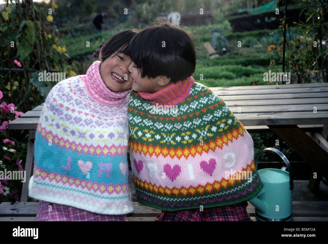 Twin Chinese girls cuddling each other in an English garden Stock Photo Alamy