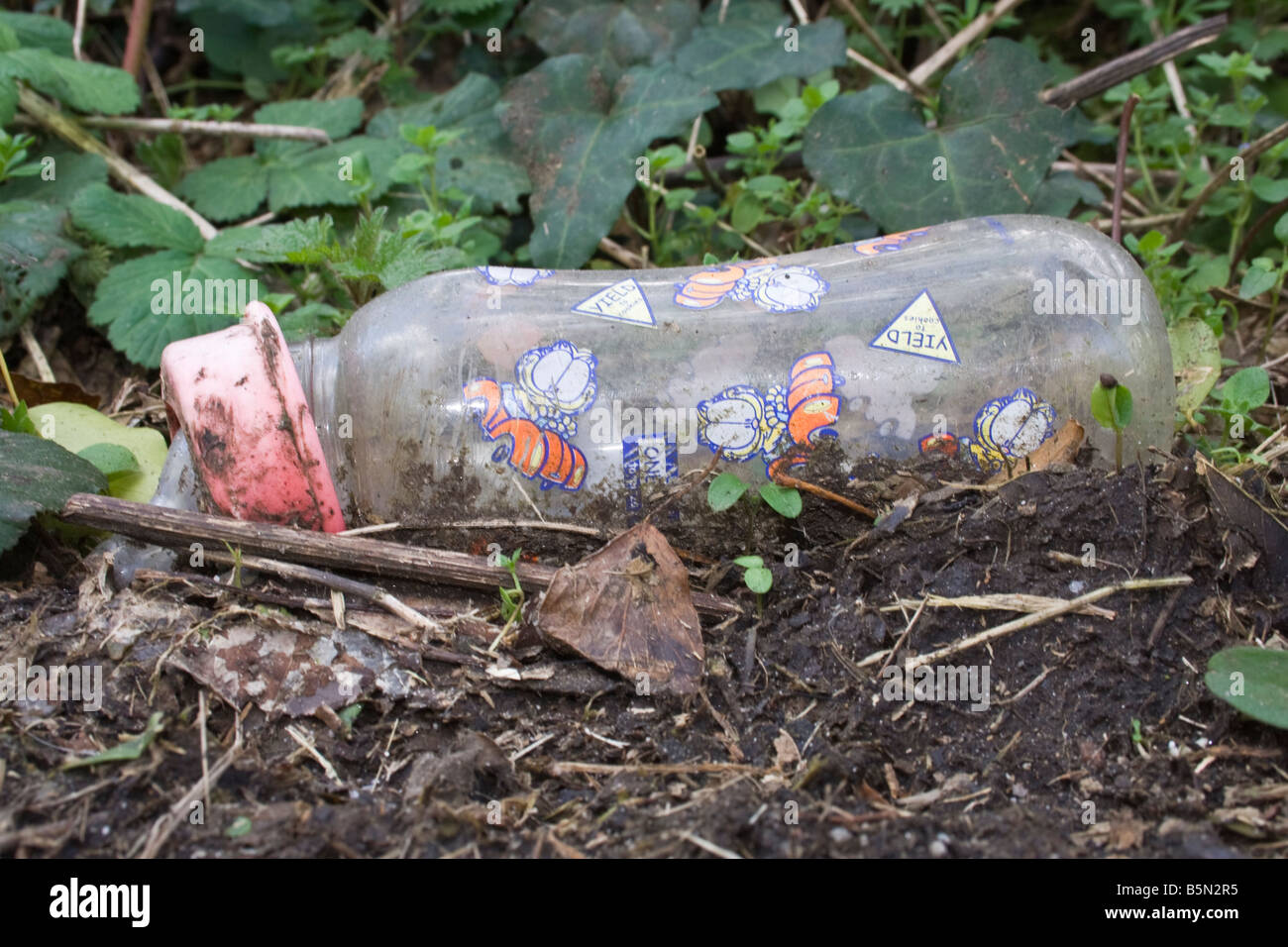 A baby bottle that has been thrown away in a hedgerow. Stock Photo
