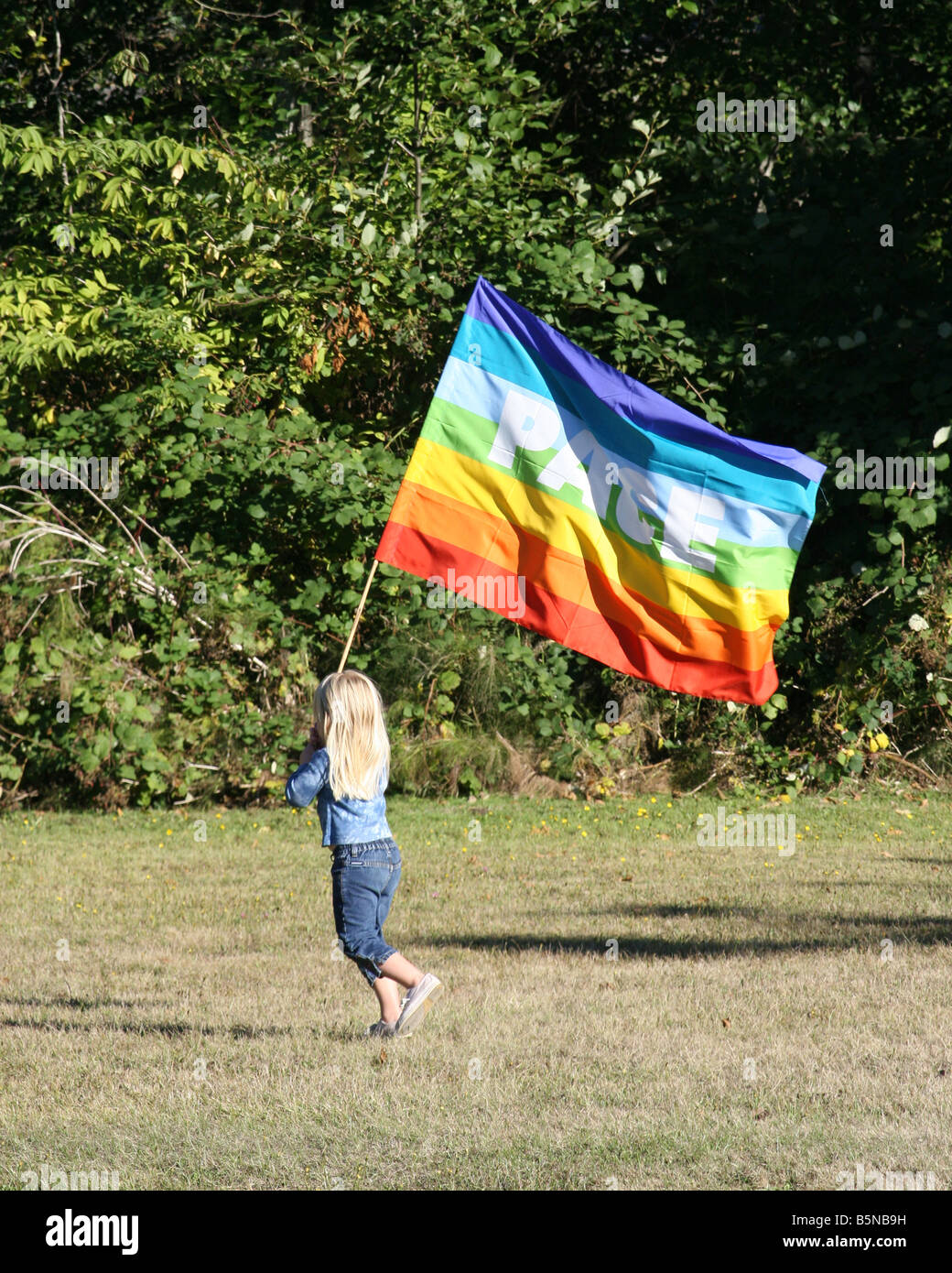 Peace march with young girl walks alone with a peace flag in the bright sun. Stock Photo